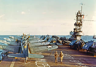 USS Santee (ACV-29) Douglas SBD-3 Dauntless scout-bombers and Grumman F4F-4 Wildcat fighters on the ship's flight deck during Operation Torch, the November 1942 invasion of North Africa. Note the yellow Operation Torch markings visible around the fuselage stars of some of these airplanes. Also note the distance and target information temporarily marked on the carrier's flight deck. Photographed by Lieutenant Horace Bristol, USNR.  Some published sources state that this photo was taken on USS Sangamon (ACV-26). However, the camouflage pattern on her island definitely identifies the ship as Santee.  Official U.S. Navy Photograph, now in the collections of the National Archives.