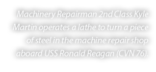 Machinery Repairman 2nd Class Kyle Martin operates a lathe to turn a piece of steel in the machine repair shop aboard...