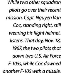 While two other squadron pilots go over their recent mission, Capt. Nguyen Van Coc, standing right, still wearing his...