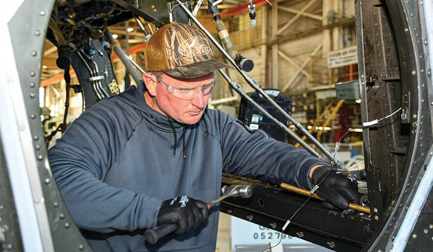 Chris Willis, a V-22 aircraft mechanic at Fleet Readiness Center East (FRCE), performs maintenance on a V-22 Osprey inside the depot’s hangar while utilizing the appropriate personal protective equipment. FRCE recently earned the Chief of Naval Operations (CNO) Shore Safety Award in the Large Industrial Activity category for the second consecutive year for its continued efforts toward safety and occupational health excellence in fiscal year 2024.