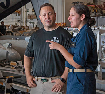 From left, Aviation Machinist's Mate Senior Chief Dan Reyes and his daughter, U.S. Midshipmen 2nd Class Gabriella Reyes, from Miami, Florida talk in the Hanger Bay of the aircraft carrier USS Nimitz (CVN 68) in the South China Sea, June 11, 2025. Nimitz is underway in the U.S. 7th Fleet area of operations on a scheduled deployment, demonstrating the U.S. Navy's unwavering commitment to a free and open Indo-Pacific. (U.S. Navy Photo by Mass Communication Specialist Seaman Gina Gallia)