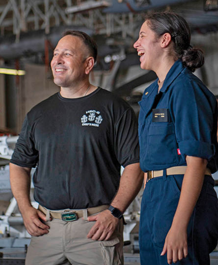 From left, Aviation Machinist's Mate Senior Chief Dan Reyes and his daughter, U.S. Midshipmen 2nd Class Gabriella Reyes, from Miami, Florida talk in the Hanger Bay of the aircraft carrier USS Nimitz (CVN 68) in the South China Sea, June 10, 2025. Nimitz is underway in the U.S. 7th Fleet area of operations on a scheduled deployment, demonstrating the U.S. Navy's unwavering commitment to a free and open Indo-Pacific. (U.S. Navy Photo by Mass Communication Specialist Seaman Apprentice Frankie M. Guage)