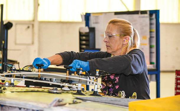250327-N-DG679-1048 JACKSONVILLE, Fla. (March 27, 2025) Charlotte Miller, a sheet metal mechanic at Fleet Readiness Center Southeast (FRCSE), prepares to use a drill guide fixture on the center wing section to create precise holes during service life extension program upgrades on a T-45 Goshawk wing. The T-45 Goshawk is a jet trainer aircraft used by the U.S. Navy and Marine Corps for intermediate and advanced pilot training.  (U.S. Navy photo by Toiete Jackson)