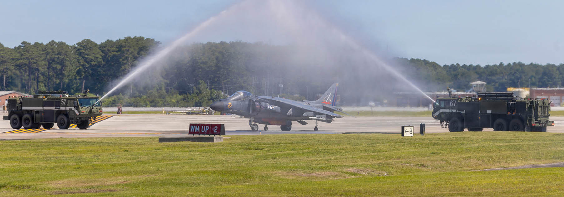 A U.S. Marine Corps AV-8B Harrier II with Marine Attack Squadron (VMA) 223, Marine Aircraft Group 14, 2nd Marine Aircraft Wing, passes under a water salute at Marine Corps Air Station Cherry Point, June 3, 2026. The “sundown” of the AV-8B Harrier II, an iconic aircraft that has supported joint and Marine Corps operations for over 40 years, also represents the dawn of a new era; it paves the way for 2nd MAW’s full transition to the F-35B and C Lightning II. VMA-223 is the U.S. Marine Corps' last operational Harrier squadron. (U.S. Marine Corps photo by Lance Cpl. Bryan Giraldo)