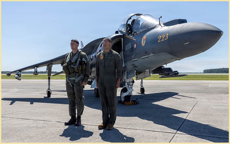 U.S. Marine Corps Lt. Col. John B. Cumbie, left, a native of Texas and the commanding officer of Marine Attack Squadron (VMA) 223, Marine Aircraft Group 14, 2nd Marine Aircraft Wing and Cpl. Myles J. Howard a native of Georgia, a fixed-wing aircraft mechanic with VMA-223, stand at attention in front of an AV-8B Harrier II at Marine Corps Air Station Cherry Point, June 3, 2026. The “sundown” of the AV-8B Harrier II, an iconic aircraft that has supported joint and Marine Corps operations for over 40 years, also represents the dawn of a new era; it paves the way for 2nd MAW’s full transition to the F-35B and C Lightning II. VMA-223 is the U.S. Marine Corps' last operational Harrier squadron. (U.S. Marine Corps photo by Lance Cpl. Donovan Pimentel)