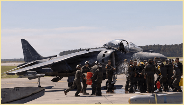 U.S. Marines with Marine Attack Squadron (VMA) 223, Marine Aircraft Group 14, 2nd Marine Aircraft Wing, and families celebrate with water and champagne at Marine Corps Air Station Cherry Point, June 3, 2026. The “sundown” of the AV-8B Harrier II, an iconic aircraft that has supported joint and Marine Corps operations for over 40 years, also represents the dawn of a new era; it paves the way for 2nd MAW’s full transition to the F-35B and C Lightning II. VMA-223 is the U.S. Marine Corps' last operational Harrier squadron. (U.S. Marine Corps photo by Lance Cpl. Michael Robinson)